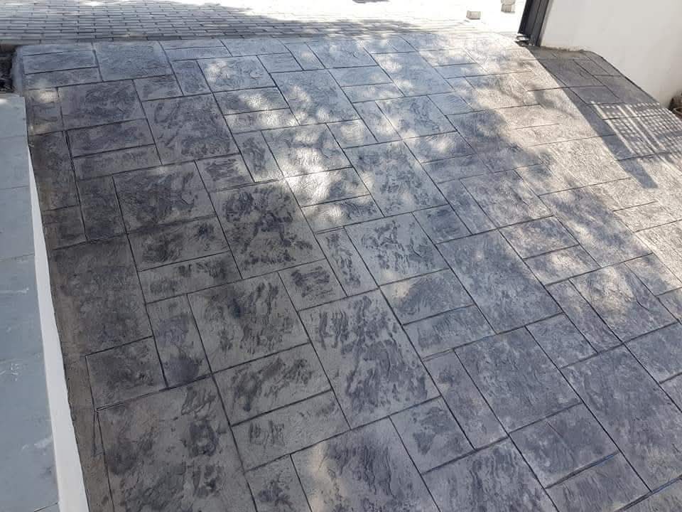 Slate-grey stamped concrete courtyard under tree shade