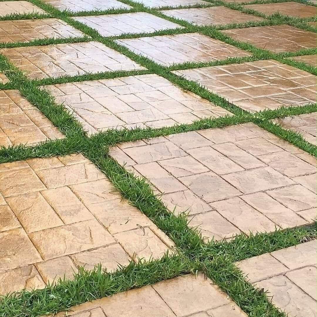 Sandstone-toned stamped concrete slabs set into a lawn with grass joints