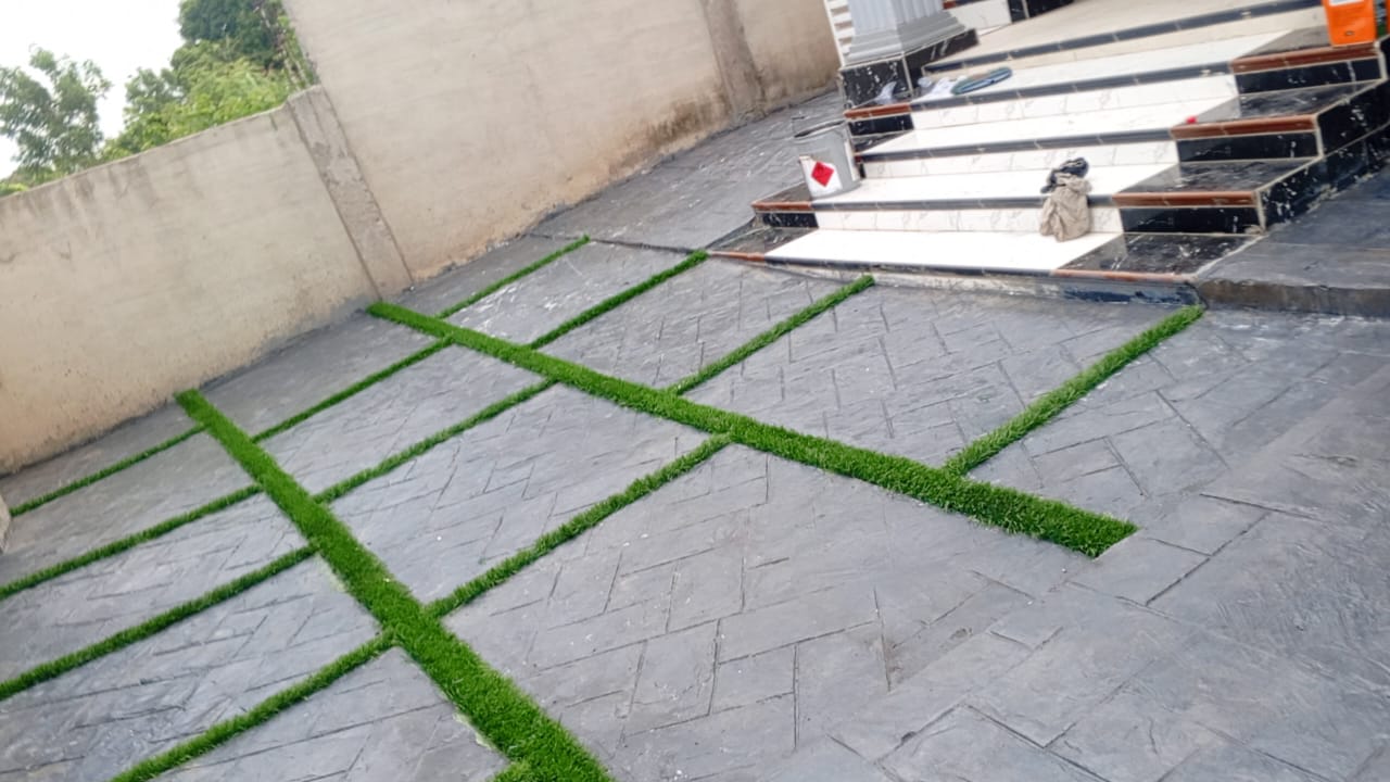 Grey stamped concrete terrace with artificial grass inlay strips