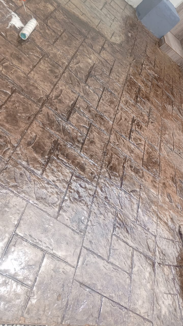 Stamped concrete floor being sealed with a roller, herringbone pattern